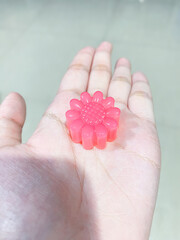 Flower shaped watermelon flavored jelly on my hand.