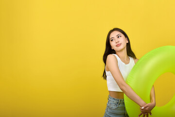 Slender young Asian brunette modestly holding an inflatable circle, looking away. Cute cute teenage...
