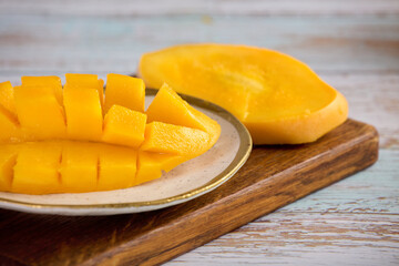 Juicy freshly chopped mango on a wooden stick. An appetizing piece of bright mango on a cutting board.