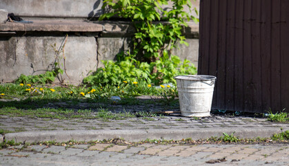 Outside stands an empty white bucket.