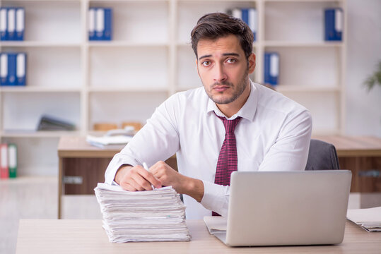 Young male employee and too much work at workplace