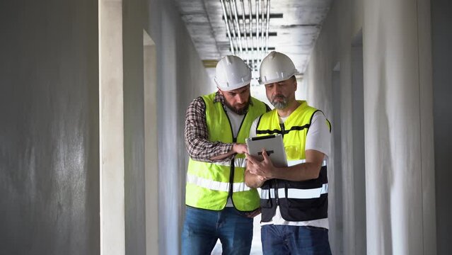 team of Construction workers Senior architect or civil engineer and foreman walking and discussion to inspection structure interior apartment with tablet at construction site. indoors building project
