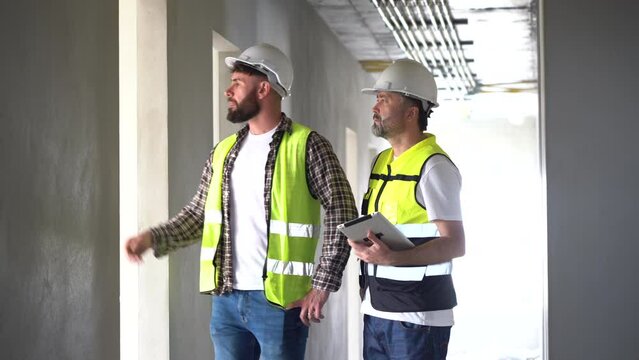 team of Construction workers Senior architect or civil engineer and foreman walking and discussion to inspection structure interior apartment with tablet at construction site. indoors building project