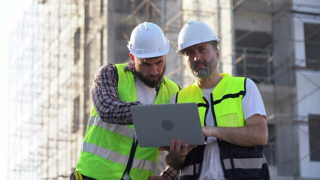 team of Construction workers Senior architect or civil engineer and foreman walking and discussion to inspection structure apartment with computer laptop at construction site. building project