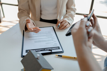 A realtor is explaining home insurance documents to a buyer in office at the company, Sign home...