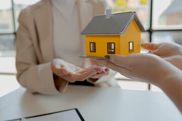 A real estate agent sits in her office, The salesperson is presenting what the home the customer is about to buy looks like, The broker is calculating the buyer's monthly instalment payments.