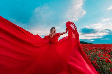 Woman poppy field red dress. Happy woman in a long red dress in a beautiful large poppy field. Blond stands with her back posing on a large field of red poppies - Powered by Adobe