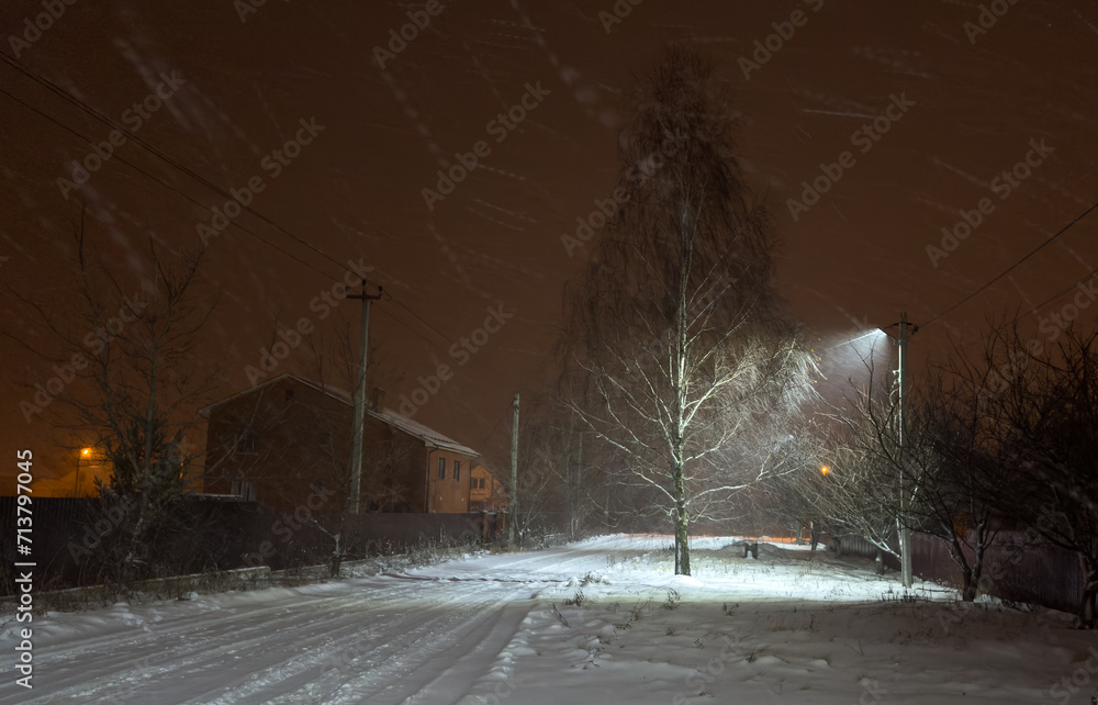 Poster It's snowing at night in the light of a lantern on a pole