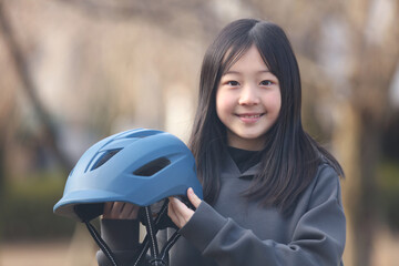 自転車用ヘルメットを持つ女の子 - obrazy, fototapety, plakaty