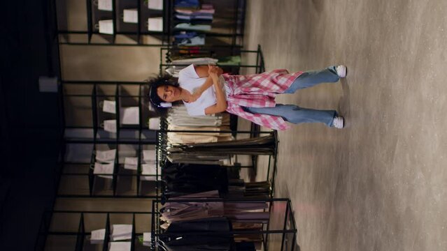 Dancing queen on a vertical plan for Instagram reels, a woman dances in a clothing store with headphones on, she dances very cool in a clothing store with headphones on.