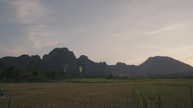 A powered parachute at Vang Vieng, Laos during sunset with a backdrop of karst mountains
