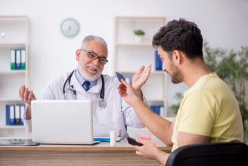 Fototapeta premium Young male patient visiting old male doctor
