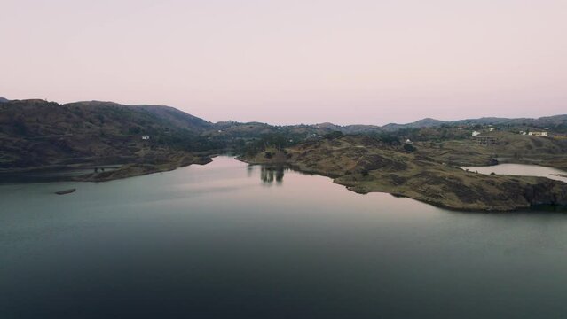 aerial drone shot flying forward over Alsigarh lake Rayta bahubali aravalli hills just outside udaipur a fast growing tourist spot in the city of lakes tourist spot in Rajasthan India shot at dusk