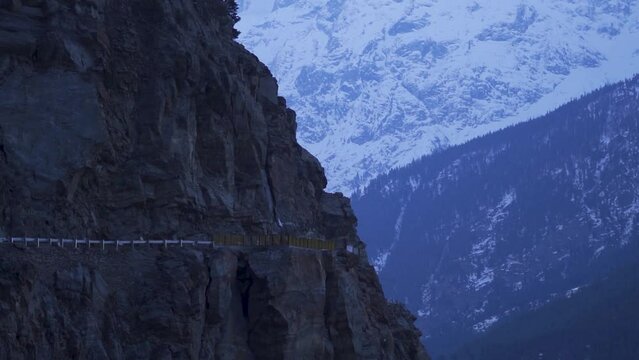 Closeup shot of Kalpa suicide point cliff besides the road in front of the snow covered Himalayas at Kalpa in Kinnaur, Himachal Pradesh, India. Dangerous cliff road in the Himalayas. Nature background