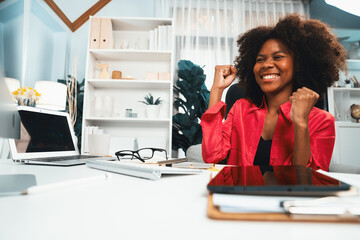 African woman blogger exited with happy face, looking on screen with valued stock market achievement at high profit. Concept of exchange investment online in trading application on pc. Tastemaker.