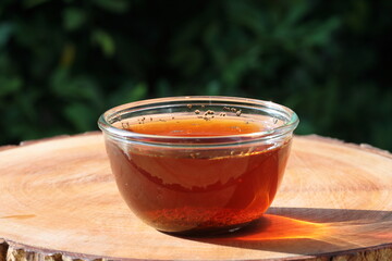 Tea being poured into glass tea cup. Pouring black tea in cup. Fresh hot herbal tea healthy morning drink on nature background.