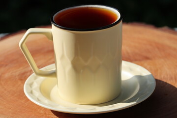 Cup Of Tea Closeup Over Nature Green Background. Pouring green tea in cup. Glass tea pot. Hot...