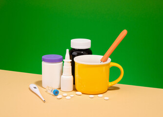 Disease treatment, pills, nasal spray and thermometer. Yellow beverage cup.