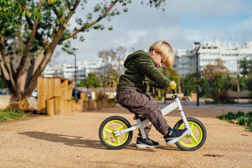 A little boy is on a bike ride.3 year old blond boy plays and enjoys a sunny day in the park on a...
