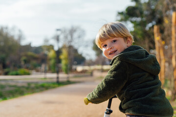 Fototapeta premium A little boy is on a bike ride.3 year old blond boy plays and enjoys a sunny day in the park on a bicycle