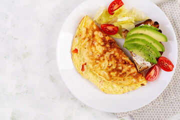 Omelette with tomatoes and toast with avocado on white plate.  Frittata - italian omelet. Top view, flat lay