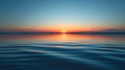 Smooth surface of a calm lake reflecting the sky at sunset, minimal ripples.