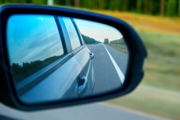 The road in the rear view mirror of a car