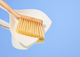 A hand brush with thick bristles and a white dustpan. Copy space for text.
