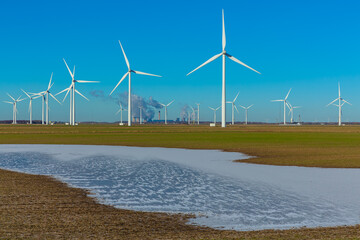 Wind turbine farm near Goole in East Yorkshire with frozen flood water and  Drax Power Plant in the...