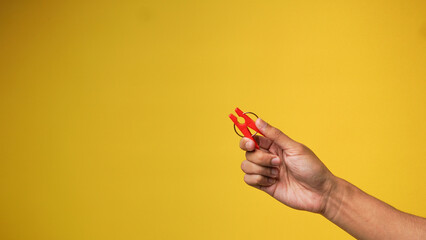 Men's hands holding clothespins on a yellow orange background