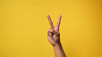 Man's hand pointing finger at camera on yellow background
