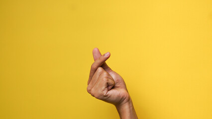 Men's hands give a love gesture on a yellow background