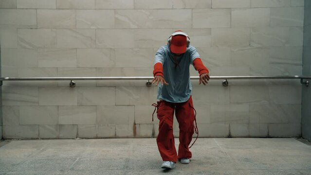 Handsome choreographer practice street dance in gray background. Young attractive b boy dancer perform while wearing stylish cloth. Feeling of lively step. Copy space. Outdoor sport 2024. Sprightly.