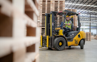 Warehouse worker wears safety helmet driving forklift truck in pallet factory. Skilled male...