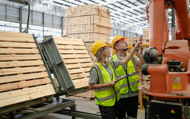 Engineer colleague team working in hardwood furniture factory examining production machine for...