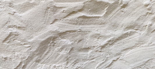 The rough texture of a poorly plastered light-colored wall. An uneven surface with bumps and...