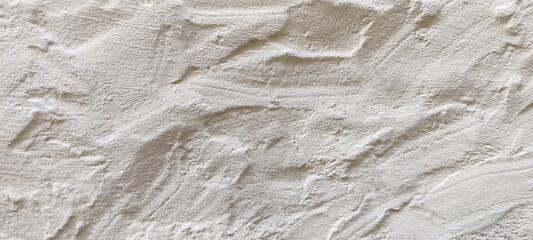 The rough texture of a poorly plastered light-colored wall. An uneven surface with bumps and depressions. Background for the design. Full frame. Copy space. Mock-up.
