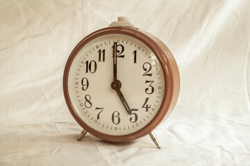 Fototapeta na wymiar vintage alarm clock on dirty white cloth background.