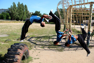 a guy in black pants does a somersault in parkour style at the stadium