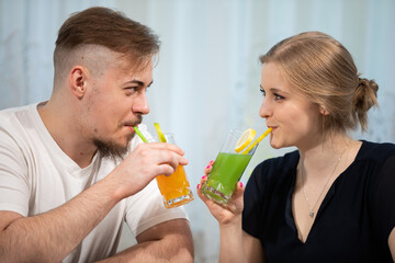 Girl and boy toast with colorful drinks with straws.