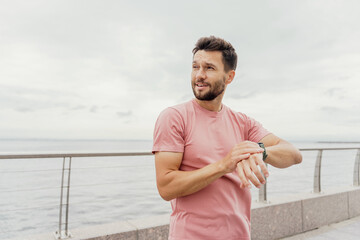 Man checking watch during workout on a cloudy day by the sea.