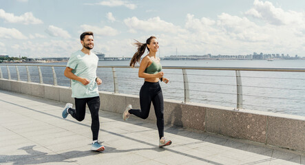 Couple running together on a riverside promenade, staying fit.