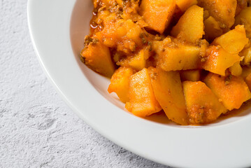 Minced meat and potato dish on white porcelain plate on stone table