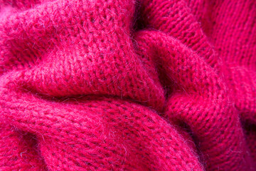 The red knitted fabric is handmade. Background. Hobby.