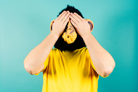Monkey Masked Person Covering Eyes with Hands, See No Evil Concept