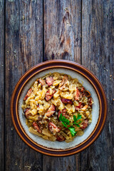 Cooked cabbage with sliced sausage on wooden table
