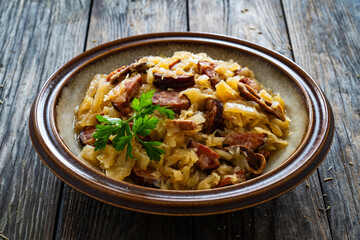 Cooked cabbage with sliced sausage on wooden table
