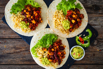 Chili con carne with rice on tortilla on wooden table
