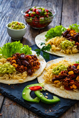 Chili con carne with rice on tortilla on wooden table
