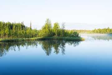 Fototapeta na wymiar A scenery of a small lake on a calm summer morning near Kuusamo, Northern Finland